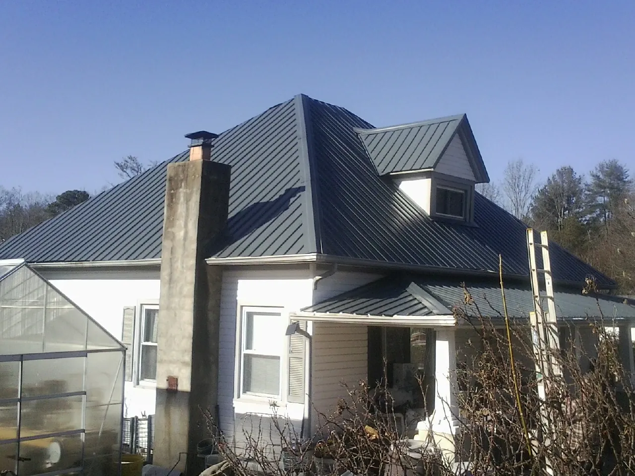 Dark blue standing seam metal roof on a white farmhouse with dormer — Slate & Tile Roof Repair by Roofing Brothers in Perkiomenville