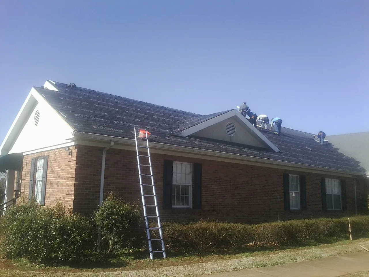 Crew tearing shingles off a brick ranch roof with a ladder set — Metal Roof Repair work by our crew in Perkiomenville