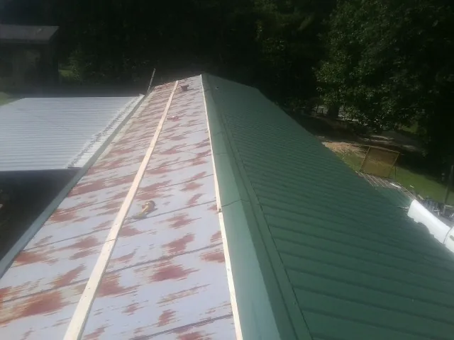 Old rusted panels beside newly installed green metal roofing — Wind Damage Roof Repair by Roofing Brothers in Perkiomenville