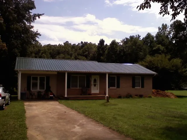 Dark green metal roof on a brick ranch with a covered porch in Perkiomenville