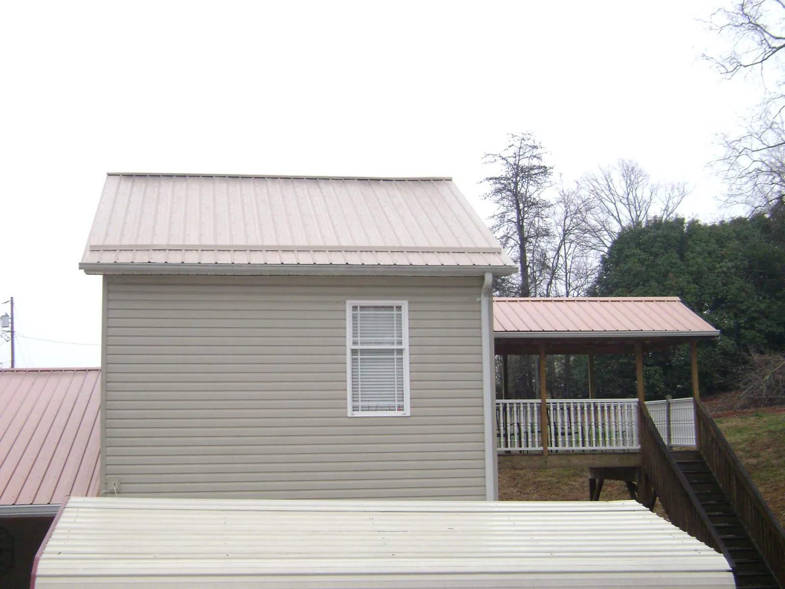 Tan metal roofs on a two story addition and attached porch, from a Roof Replacement job in Perkiomenville
