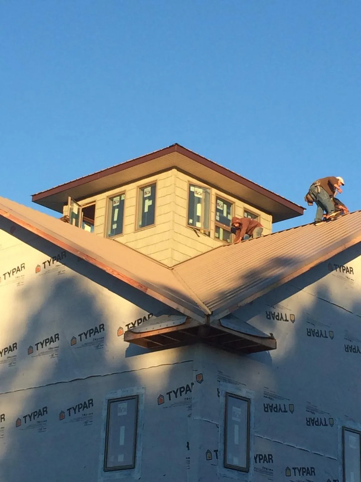 Roofers working around a rooftop cupola on a new metal roof at sunset — Roof Waterproofing in Perkiomenville by Roofing Brothers